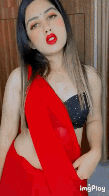 a woman is wearing a red saree and a black bra ..