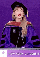 a woman in a graduation cap and gown is giving a speech .