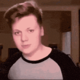a young man is making a funny face while wearing a gray and black shirt .