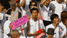 a man in a crowd holds a sign that says we are the champion