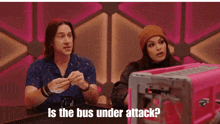 a man and a woman sitting at a table with the words is the bus under attack on the bottom