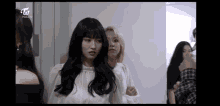 a group of girls are standing next to each other in a room and one of them is looking at the camera .
