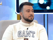 a man with a beard is wearing a white sweater with the word gant on it