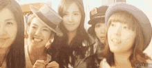 a group of young women wearing hats are standing next to each other and smiling .