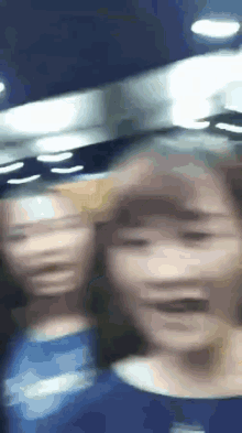 a blurry picture of two women standing next to each other in a dark room .