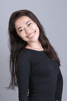 a woman with long hair wearing a black shirt is smiling