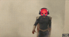 a person wearing headphones and a red mask with buzza written on the bottom