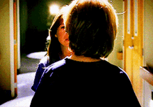 two women standing next to each other in a hallway looking at each other