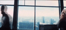 a group of people are standing in front of a large window looking out at the city .