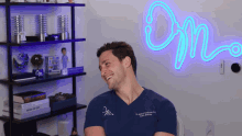 a man sitting in front of a neon sign that says " on "
