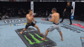 two men are fighting in a ring with a monster energy drink on the floor