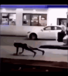 a person is doing push ups in front of a white car .