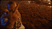a man in a hawaiian shirt is giving the middle finger in front of a fire .