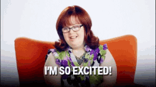 a woman with down syndrome is sitting in an orange chair and says i 'm so excited !