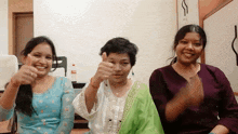 three women are giving a thumbs up and smiling