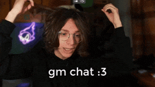 a man with glasses is holding a glowing object and says gm chat : 3 on the bottom