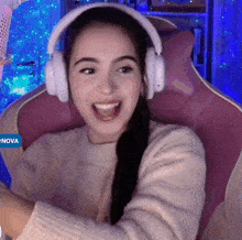 a woman wearing headphones is sitting in a pink chair with nova in the corner