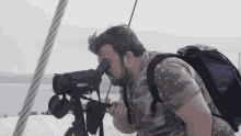 a man with a purple backpack looks through a telescope that says oregon