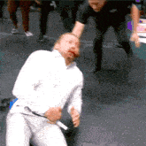 a man in a white shirt is holding a whip in his hand