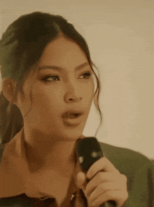 a woman singing into a microphone with a ponytail