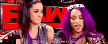 two women with purple hair are standing next to each other in front of a sign that says raw