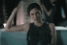 a woman in a black dress sitting on a couch