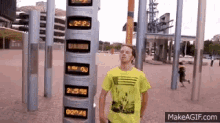 a man in a yellow shirt is standing in front of a clock that says 2:35