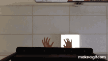 a gif of a person 's hands reaching out from behind a shelf