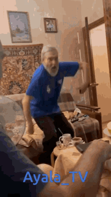 a man in a blue shirt is dancing in a room with ayala_tv written in blue