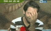 a man covering his face with his hand in front of a screen that says star news