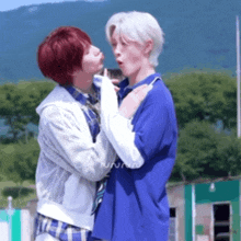 a couple of boys are standing next to each other and kissing .