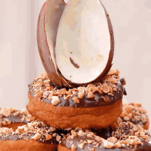 a stack of chocolate donuts with nuts and a chocolate egg on top