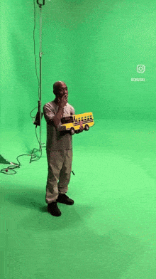 a man is holding a toy school bus on a green screen