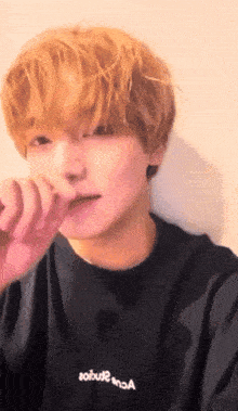 a young man with blonde hair is wearing a black shirt that says aobut2
