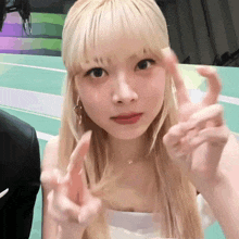 a woman with blonde hair making a peace sign