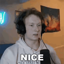 a young man wearing headphones and a hoodie is talking into a microphone .