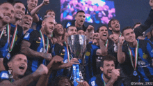 a group of soccer players are celebrating with a trophy in front of them