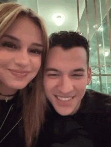 a man and a woman are posing for a picture together and smiling for the camera .