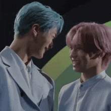 a man with blue hair and a woman with pink hair are looking at each other