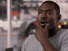 a man with his mouth open is holding his hand to his chin and looking surprised .