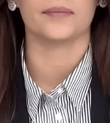 a close up of a woman 's neck and collar with a striped shirt and earrings .