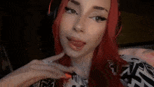 a woman with red hair and a piercing in her tongue is wearing headphones .