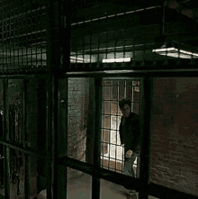 a man is standing in a prison cell with bars