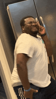 a man wearing glasses and a white shirt is making a peace sign