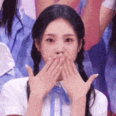 a girl covering her mouth with her hands while wearing a plaid shirt