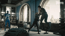 a man in a superhero costume kicks a woman in a room with the boys written on the wall