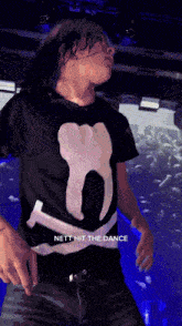 a person wearing a black shirt that says nett hit the dance is dancing