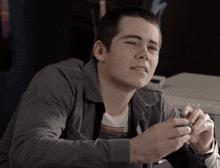 a young man in a grey striped shirt is sitting in front of a printer