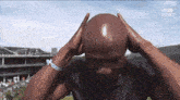 a bald man is holding his head with his hands while wearing a wristband that says ' bbc sport ' on it