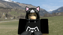 a person wearing a black cat hoodie stands in a field